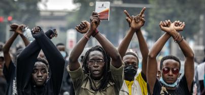 Demonstrators make signs with their arms in front of Kenyan police officers during a demonstration against tax hikes as Members of the Parliament debate the Finance Bill 2024 in downtown Nairobi, on June 18, 2024.